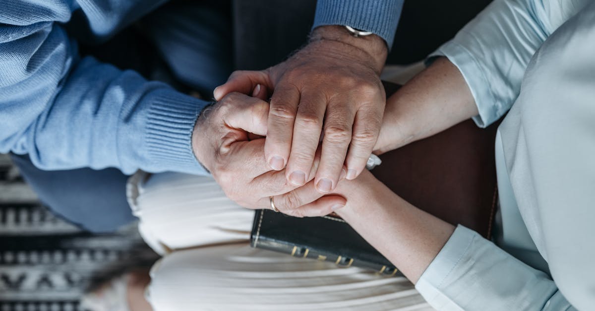 Close-up of two people holding hands, expressing comfort and empathy.